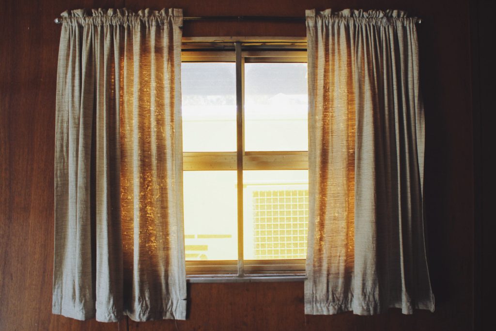 Image of a sunny window with draping curtains.