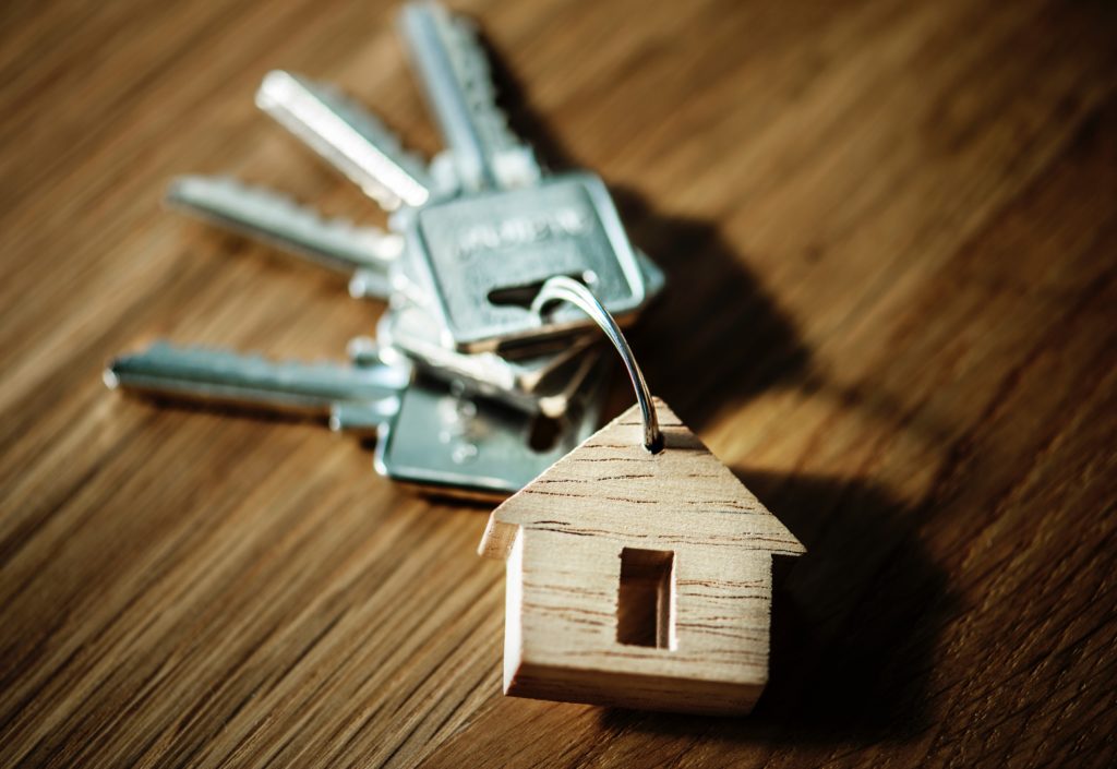 Image of a key chain with four keys and a small wooden house.