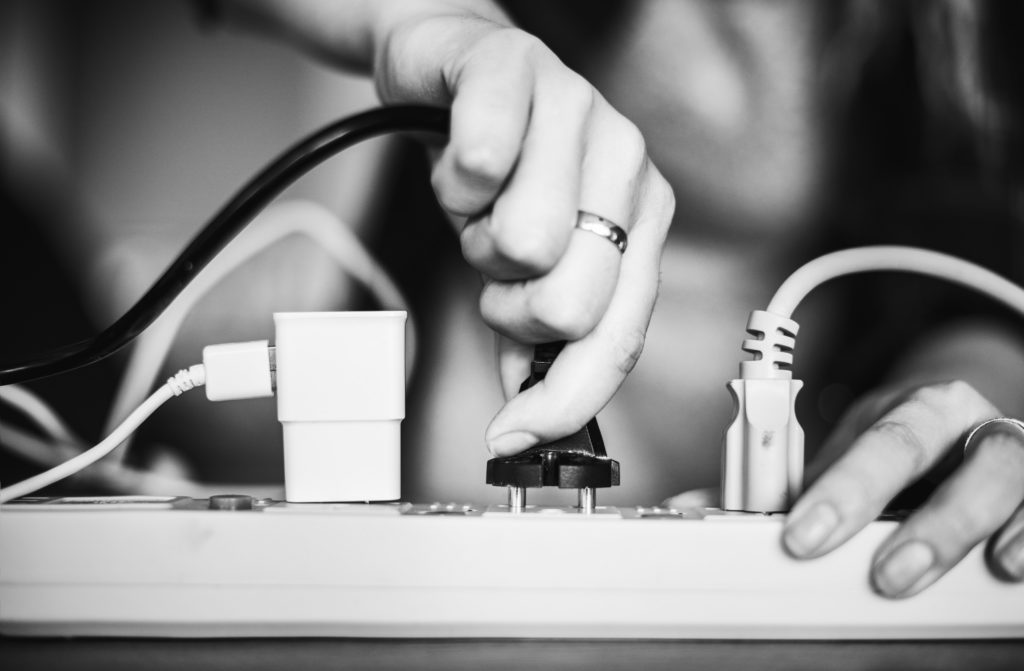 Image of a person plugging in a cord to a power strip.