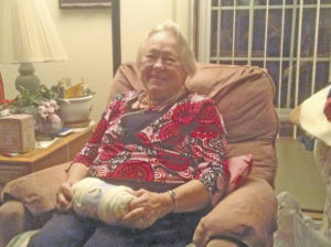 Image of a smiling older woman sitting in an easy chair with a ball of yarn in her lap.
