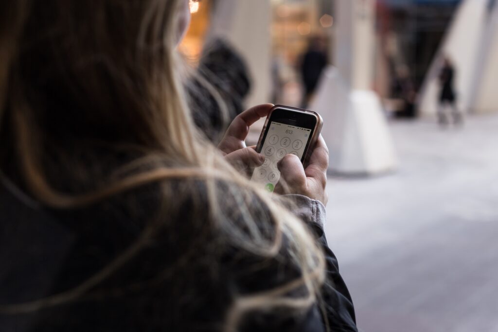 Image of a person dialing a number on their mobile phone.