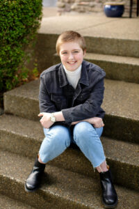 A smiling, short-haired Claire sits on the stairs.