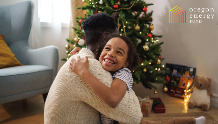 Image of a father and daughter hugging and smiling in front of a holiday tree